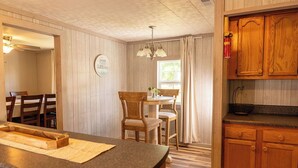 Une cuisine avec des meubles en bois, un plan de travail en granit, un coin repas avec une table et des chaises, et un luminaire suspendu.