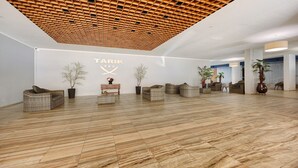 A spacious lobby with a wooden ceiling, a reception desk, wicker furniture, and a marble floor. - Studio Apartment 'Ocean - Pet Frendly' with Balcony, Wi-Fi and Air Conditioning (Portimão)