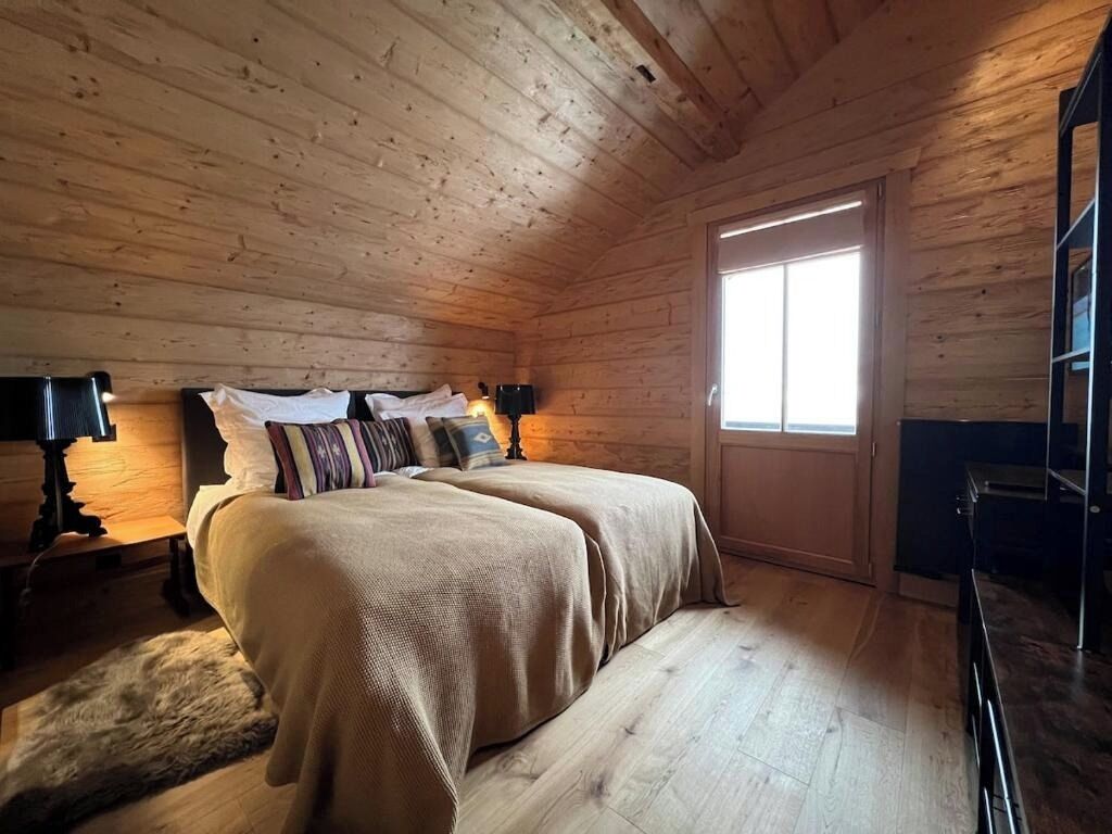 A wooden-paneled room with a bed, a window, and a desk.