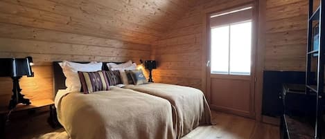 Una habitación con paneles de madera, una cama, un ventanal y un escritorio.