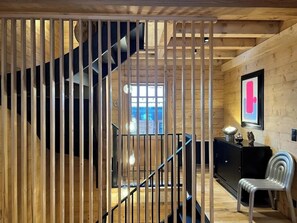 A wooden interior with a spiral staircase, a desk with a chair, and a framed picture on the wall. - -Les Clématites- Exclusive Chalet in the Heart of Villars-sur-Ollon (Villars-sur-Ollon)