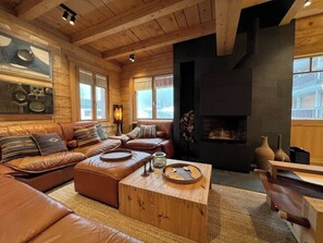 A cozy living room with a fireplace, leather sofas, and a coffee table. - -Les Clématites- Exclusive Chalet in the Heart of Villars-sur-Ollon (Villars-sur-Ollon)