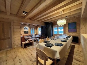 A wooden interior with a long dining table set for a meal, a fireplace, and a cozy seating area. - -Les Clématites- Exclusive chalet in the heart of Villars-sur-Ollon (Villars-sur-Ollon)