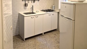 Eine kompakte Küche mit weißen Schränken, einer Spüle, einem Gasherd und einem Kühlschrank.