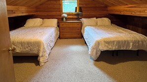 Quarto de sótão aconchegante com duas camas, uma janela pequena e um abajur.