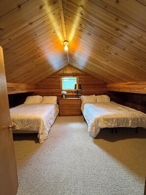 Een gezellig slaapkamer op zolder met twee bedden, een klein raam en een lamp.