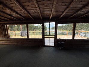 A cabin interior with a view of a deck and a lake.