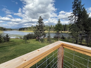 Eine Holzterrasse mit Blick auf einen See und Wald.
