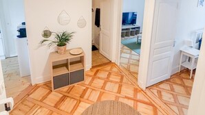 A spacious room with a wooden parquet floor, a round woven rug, a small wooden console table with a plant, and a white door leading to another room. - Central Geneva Apartment - Walk to Old Town & Lake (Genève)