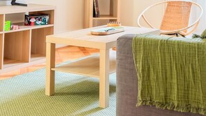 A living room with a television, a wooden coffee table, a bookshelf, and a wicker chair. - Central Geneva Apartment - Walk to Old Town & Lake (Genève)