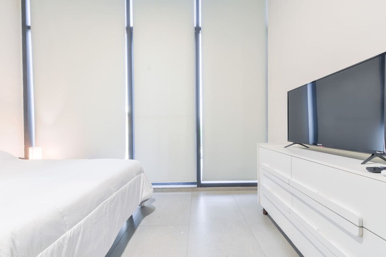 Ein Schlafzimmer mit einem Bett, einem Fernseher auf einer Kommode und einer Schiebetür.