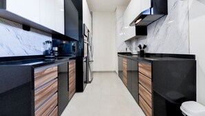 Eine moderne Küche mit schwarzen Arbeitsplatten, Holzschränken und einer Marmor-Spritzschutzwand.