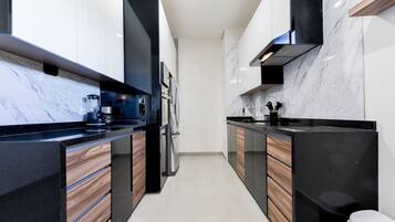 A modern kitchen with black countertops, wooden cabinets, and a marble backsplash.