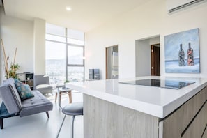 Eine moderne Küche mit einer großen Kochinsel, einem grauen Sofa und Blick auf die Stadt.