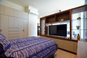 Een slaapkamer met een bed, een televisie en inbouwopslag.