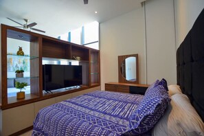 Ein Schlafzimmer mit Bett, Fernseher, Spiegel und einer eingebauten Pflanzenwand.