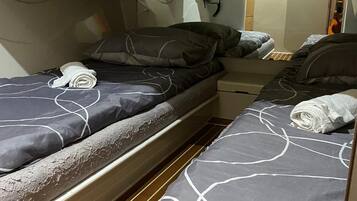 A compact cabin with two beds, each with a grey and white patterned bedspread, and a wooden floor.