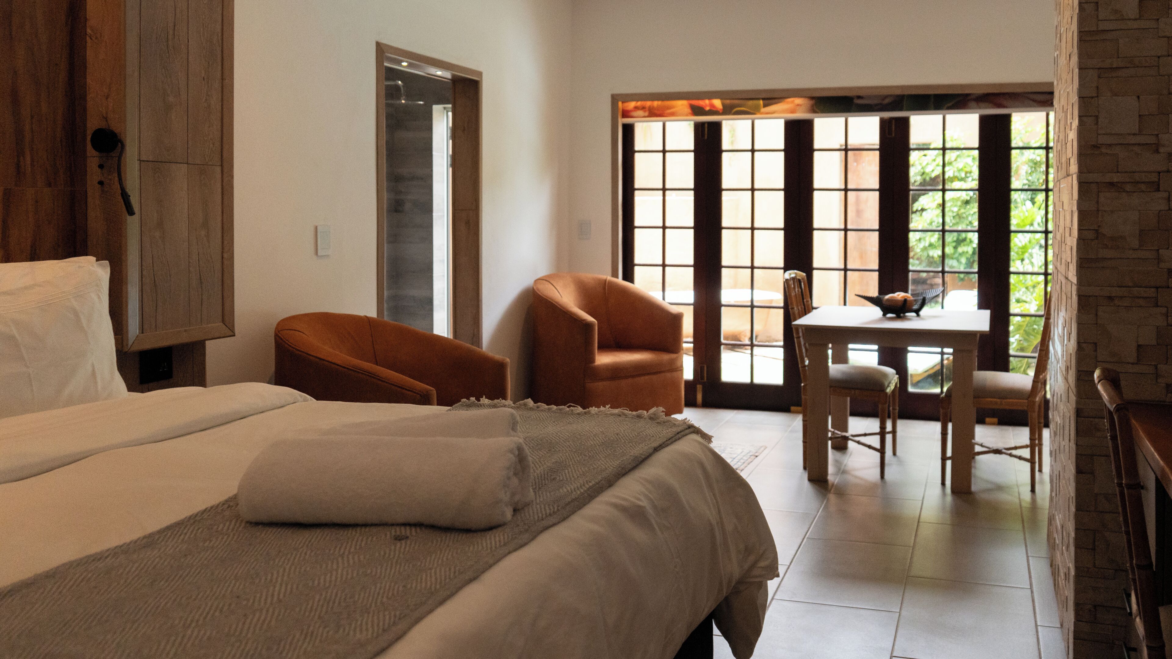 Une chambre d’hôtel avec un lit, deux chaises, une table et une vue par la fenêtre.