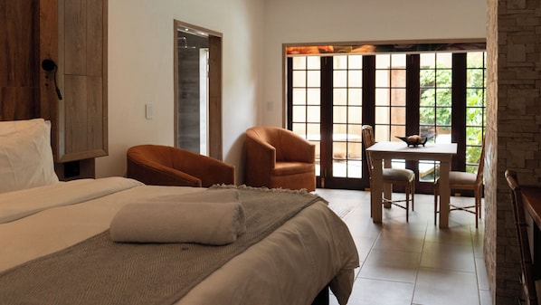 Habitación de hotel con una cama, dos sillas, una mesa y vistas por la ventana.