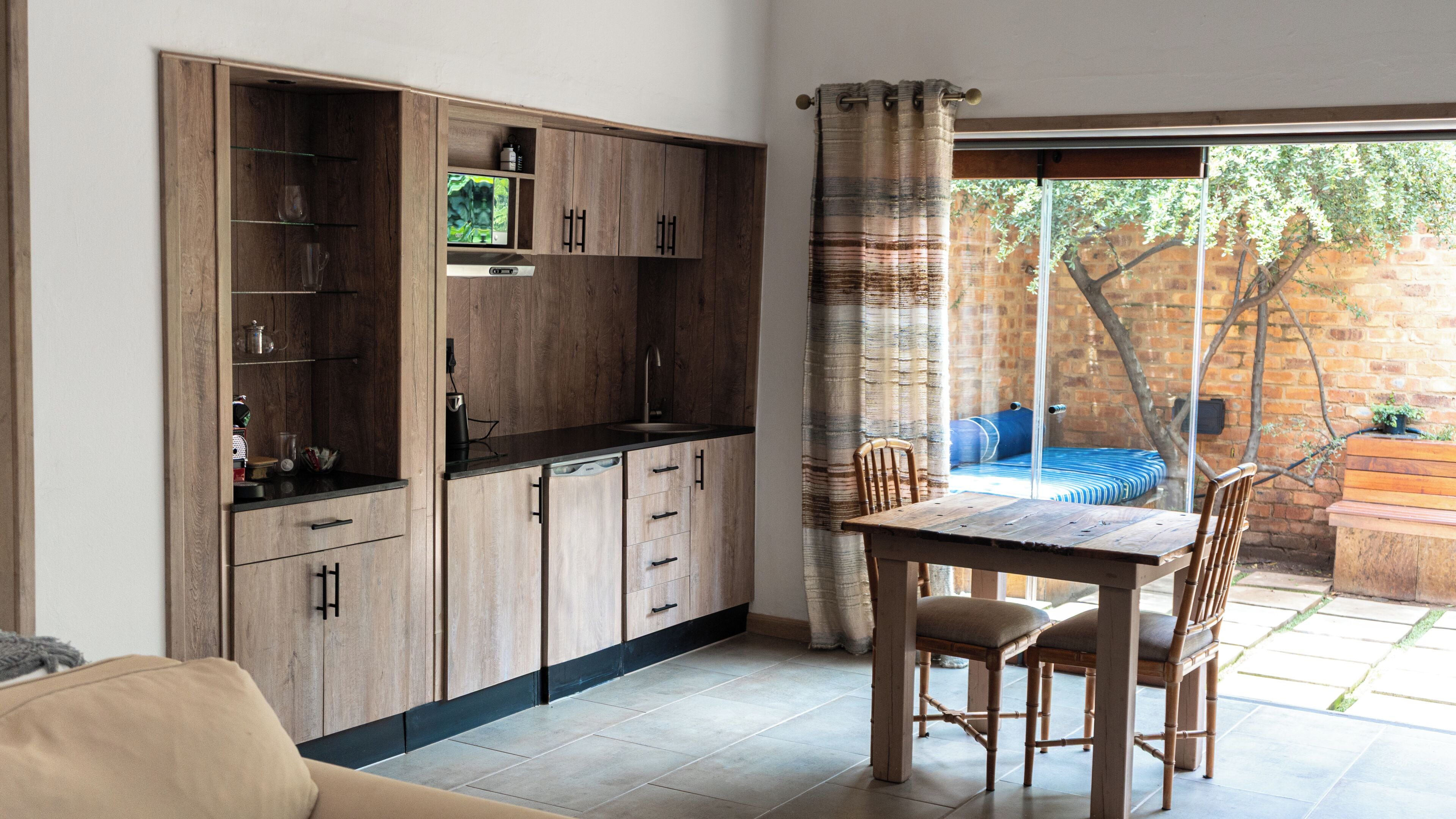 A modern kitchen with wooden cabinets, a built-in oven, and a dining area with a table and chairs.