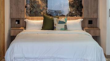 A bedroom with a large bed, two bedside tables, and a wall-mounted light fixture.