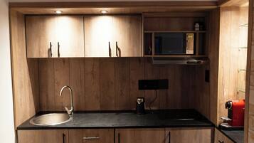 A kitchen with wooden cabinets, a stainless steel sink, a microwave, and a red coffee machine.