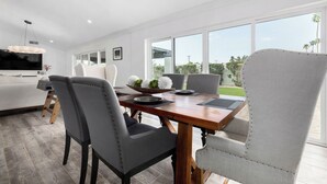 Un comedor moderno con una mesa de madera, sillas grises tapizadas y un amplio ventanal con vistas al exterior.