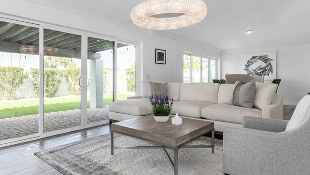 Una sala de estar moderna con un sofá color beige, una mesa de centro de madera y un sillón gris.