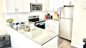 A modern kitchen with white cabinetry, stainless steel appliances, and a central island with a sink. - Modern 3 bed, 2 bath townhouse. (Vaughan)