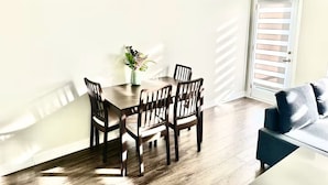 A dining area with a wooden table and chairs, a vase with flowers, and a sliding glass door. - Modern 3 bed, 2 bath townhouse. (Vaughan)