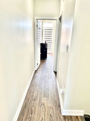 A narrow hallway with wooden flooring and white walls. - Modern 3 bed, 2 bath townhouse. (Vaughan)