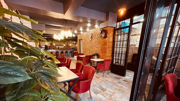 Een gezellig café met rode stoelen en tafels, een bakstenen muur en een houten vloer.