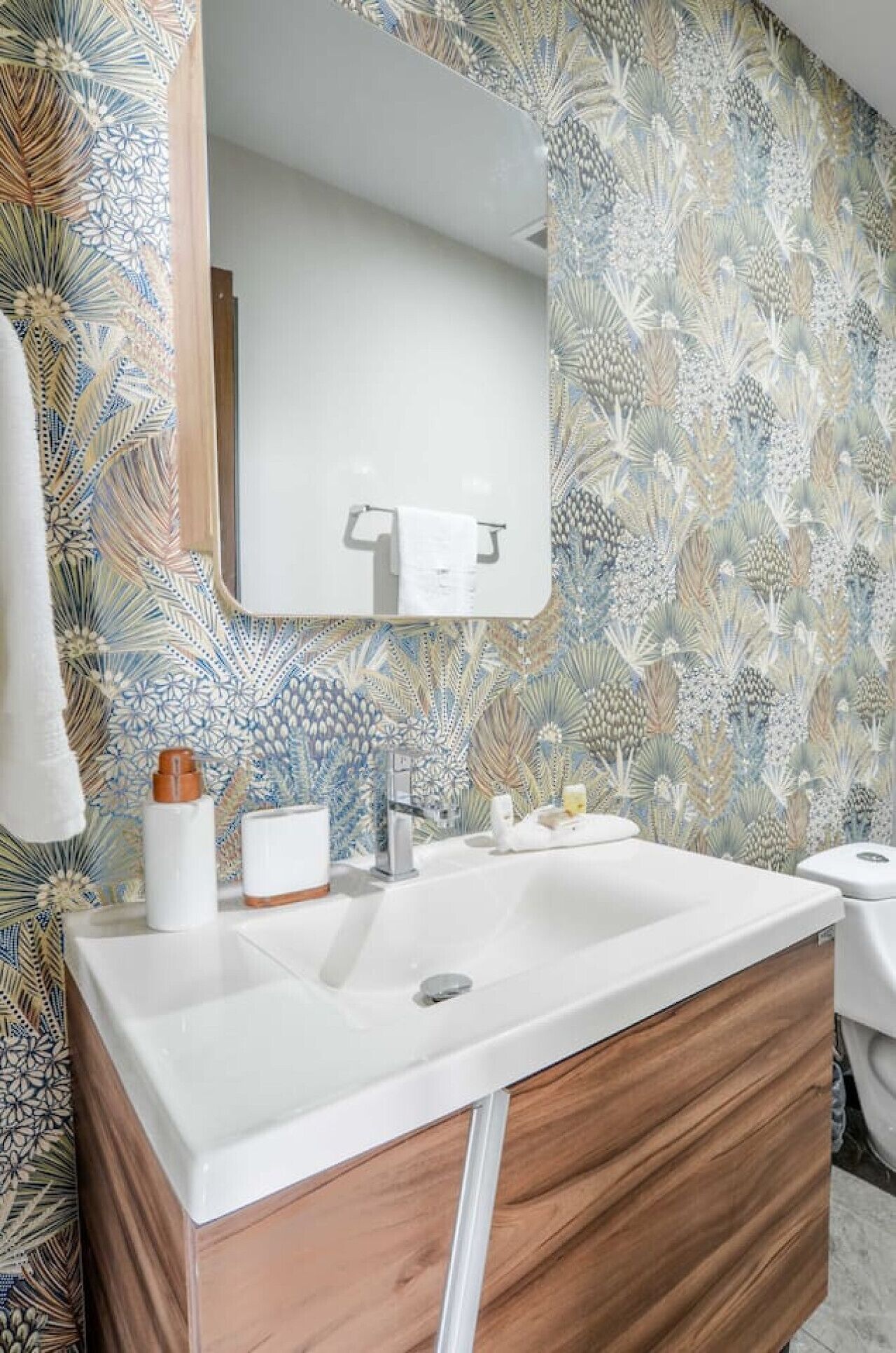 A bathroom with a white sink, wooden vanity, and a mirror above it.