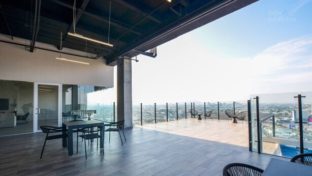 A modern office space with a large table and chairs, a glass door leading to an indoor area, and a balcony with a city view. - ¡Moderno y de lujo! - Fundidora, Cintermex, arena (Monterrey)