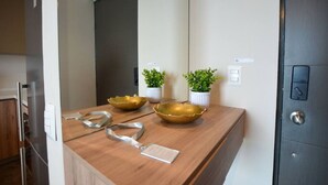 A kitchen counter with a stainless steel refrigerator, a wooden countertop, and two gold bowls. There are potted plants on the wall and a door with a handle. - ¡Moderno y de lujo! - Fundidora, Cintermex, arena (Monterrey)