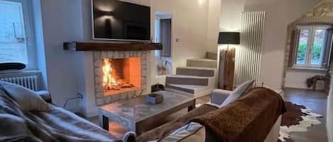 A cozy living room with a fireplace, a television, and a staircase leading to another level.