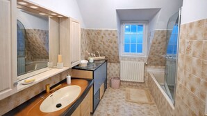 A modern bathroom with a freestanding bathtub, a large mirror, and a window with a view. - A haven of peace ideal for a family holiday, offering calm and relaxation (Plerneuf)