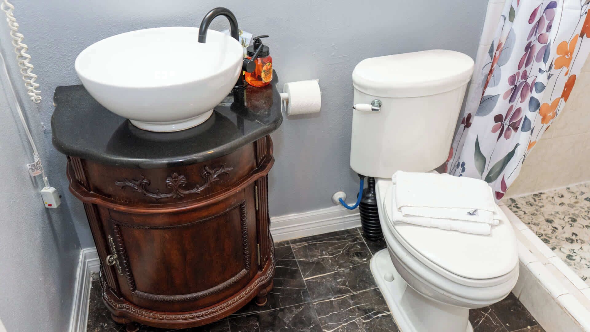 Un bagno con un mobile lavabo in legno, un lavandino bianco e un water.