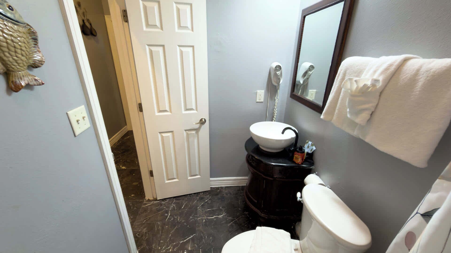 A bathroom with a white toilet, a sink with a black countertop, and a mirror above the sink.