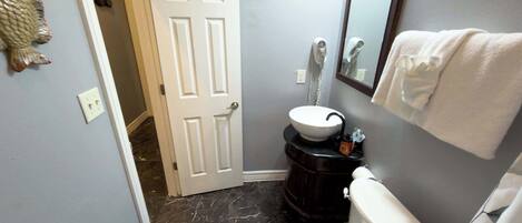 A bathroom with a white toilet, a sink with a black countertop, and a mirror above the sink.