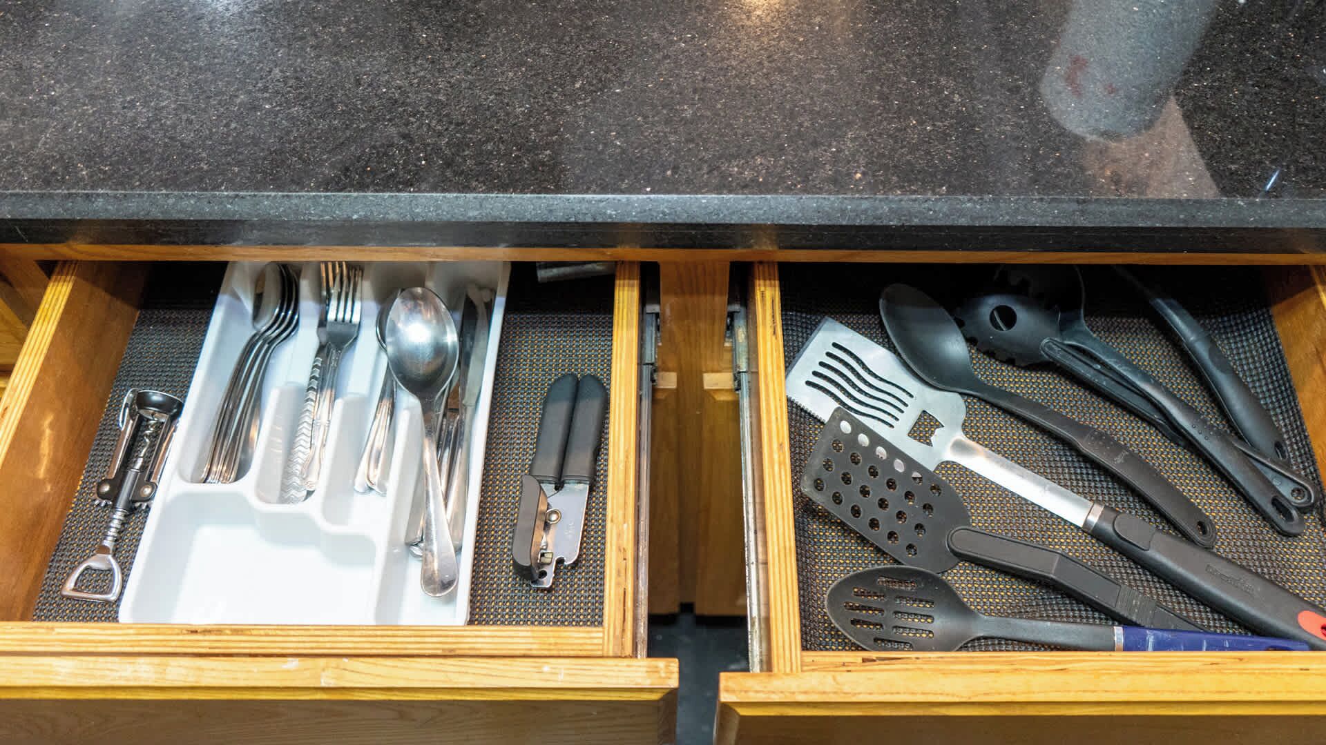 A drawer with kitchen utensils including forks, spoons, knives, and spatulas.