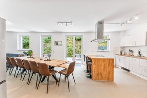 A modern kitchen with white cabinets, a wooden island, and a dining area with chairs. - LUMIFLATS Offenbrug (Offenburg)