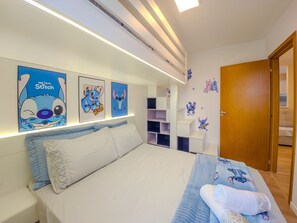 Un dormitorio con cama, mesita de noche y decoración en la pared, incluyendo a Stitch.