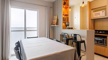 Ein Essbereich mit Tisch und Stühlen, eine Küche mit Mikrowelle und ein Fenster mit Vorhängen.