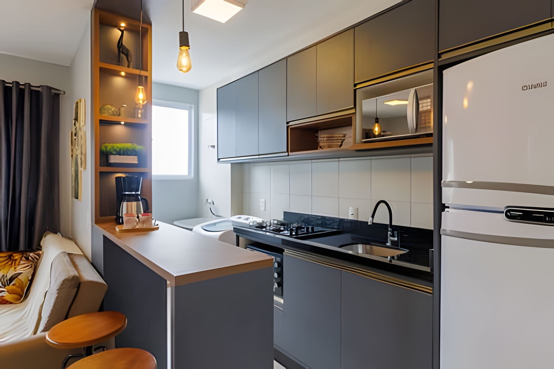 A modern kitchen with a built-in stove, a refrigerator, and a small island with stools.