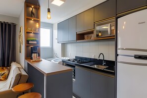 Una cocina moderna con estufa integrada, refrigerador y una pequeña isla con taburetes.