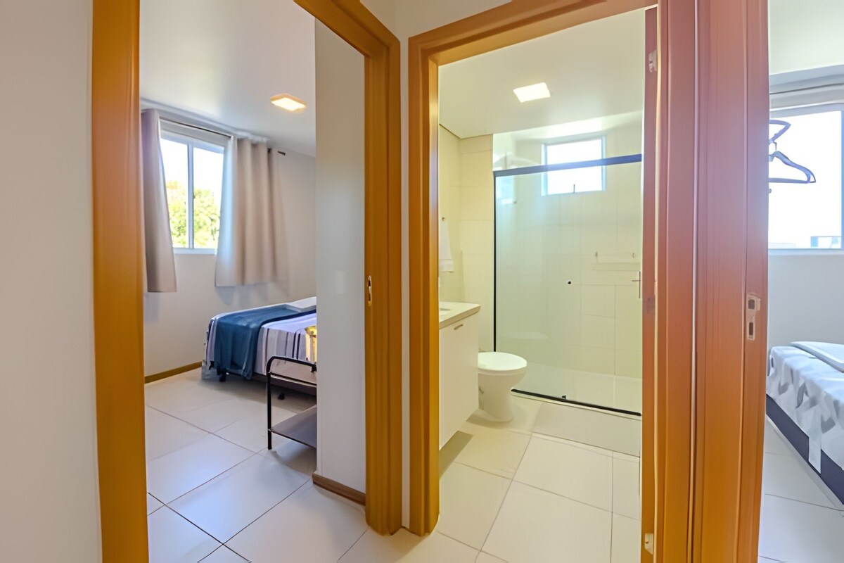 A bedroom with a bed, a bathroom with a toilet and shower, and a small kitchenette area.