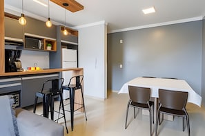 A modern kitchen with a dining area, including a table and chairs, and a built-in refrigerator. - Curta Praia do Quilombo - Lunata (Penha)