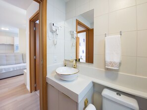 Un baño moderno con lavamanos blanco, un espejo, una toalla y un inodoro.