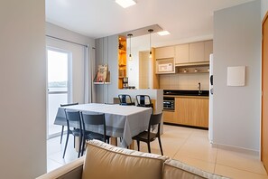 A modern kitchen with a dining area, including a table and chairs, and a view of the outside. - Curta Praia do Quilombo - Lunata (Penha)